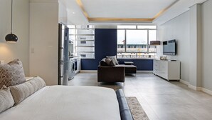 Ein modernes Hotelzimmer mit einem großen Bett, einer Couch, einem Essbereich mit Aussicht und einer Küche.