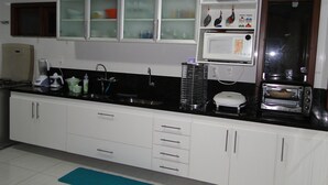 A kitchen with white cabinets, a black countertop, a microwave, a toaster, and a sink. - Excellent house, on the best beach in Itacimirim. (CAMAÇARI)
