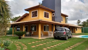 A two-story house with a swimming pool, a car parked in front, and a patio area with chairs. - Excellent house, on the best beach in Itacimirim. (CAMAÇARI)