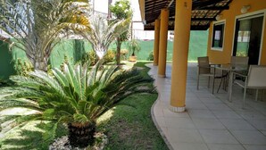 A covered outdoor area with a patio, chairs, and a palm tree. - Excellent house, on the best beach in Itacimirim. (CAMAÇARI)