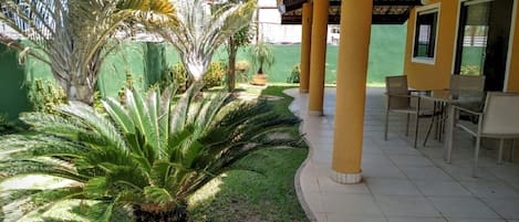 A covered outdoor area with a patio, chairs, and a palm tree.