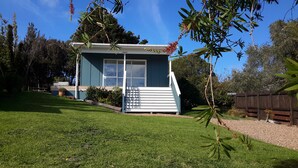 A small, single-story house with a front porch and a clear blue sky. - Cute & modern chalet, 500m to sandy beaches, close to vineyards with seaview (Oneroa)