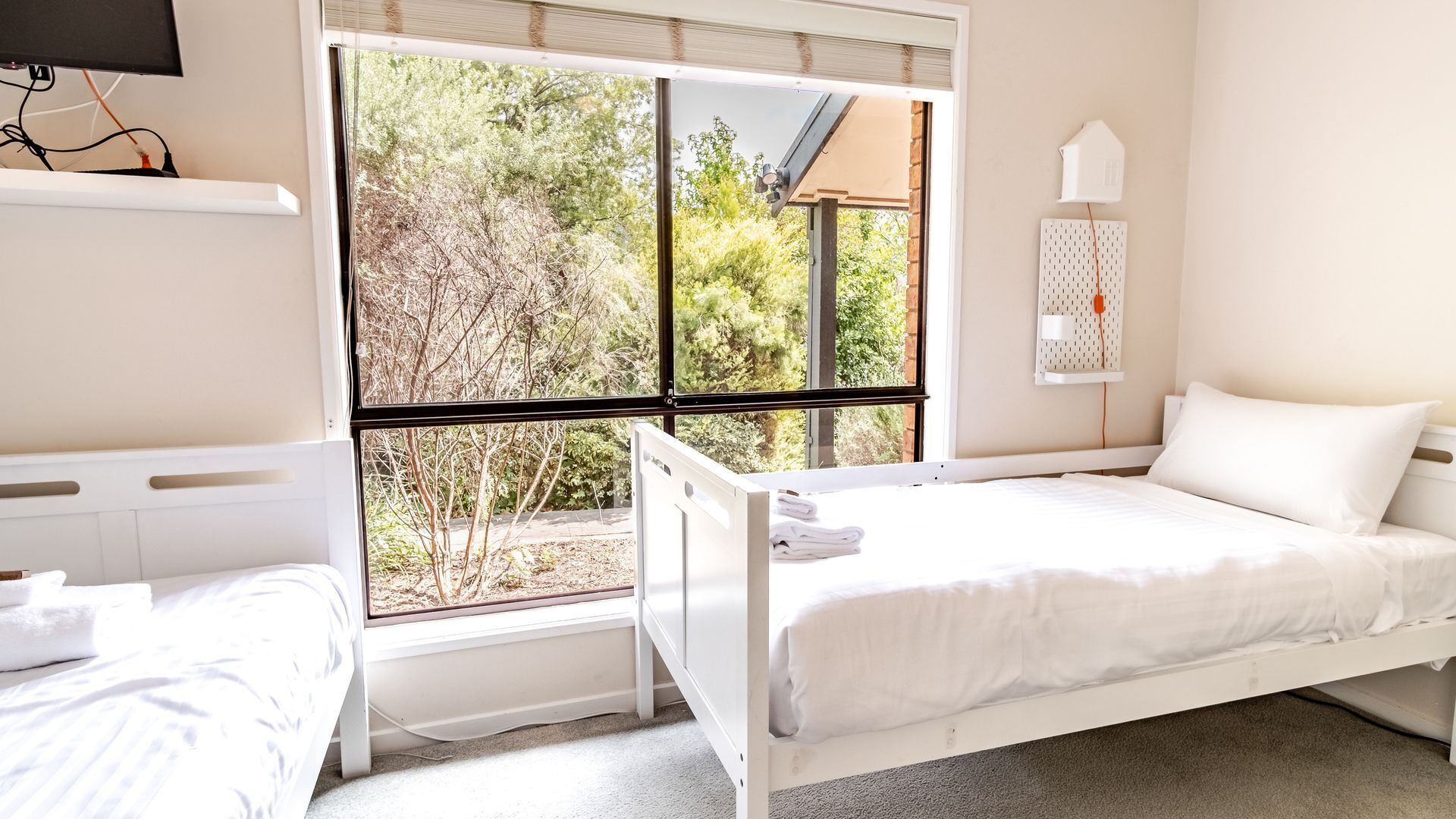 A bedroom with a bed, a window, and a wall-mounted heater.