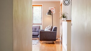 A modern living room with a grey sofa, a floor lamp, and a clock on the wall.