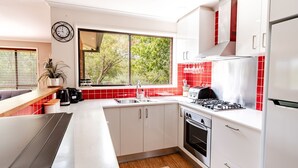 A modern kitchen with white cabinets, a stainless steel stove, and a red-tiled backsplash.