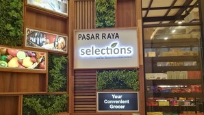 A grocery store interior with wooden shelves and a sign reading "PASAR RAYA selections".