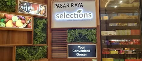 A grocery store interior with wooden shelves and a sign reading "PASAR RAYA selections".