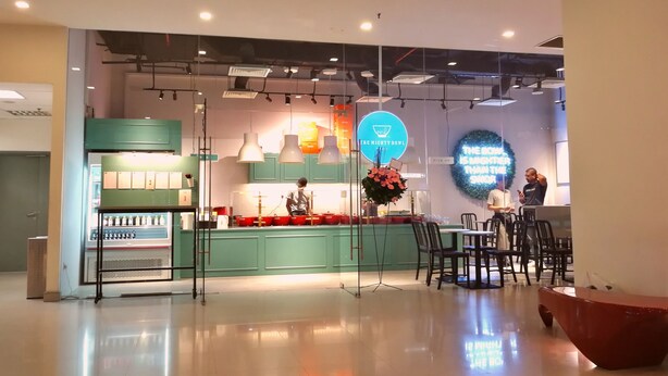 A modern restaurant interior with a counter, seating area, and a neon sign.