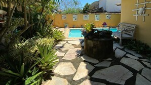 Un pati amb piscina, un camí de pedra i plantes tropicals.