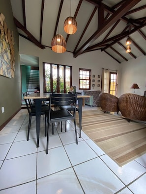 Uma sala de jantar com mesa e cadeiras, um sofá e um tapete estampado.
