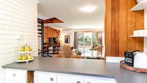 Eine Küche mit modernem Design, mit einer weißen Ziegelwand, einer Holztreppe und einem Essbereich mit Tisch und Stühlen.
