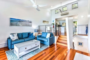 Un salon moderne avec un canapé bleu, une table basse et un escalier menant à un niveau supérieur.