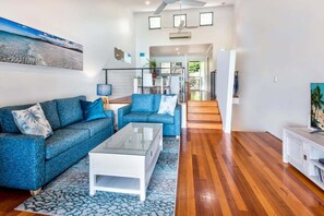 A spacious living area with a sofa set, a coffee table, and a television.