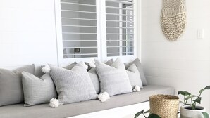 A modern living room with a grey sofa, a round wooden coffee table, and a woven rug. - The Nest - 5 minute walk to Hasting Street and Noosa Main Beach (Noosa)