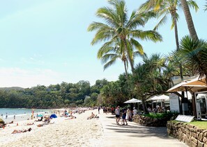 Une plage bordée de palmiers, une promenade en bord de mer et des gens qui se détendent.