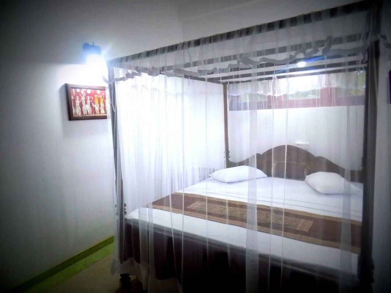 Una cama individual con dosel, una mesita de noche y una lámpara de pared.
