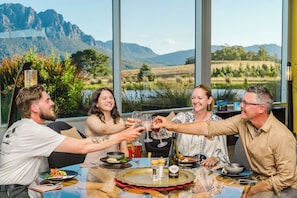 A group of people toasting at a table with a scenic view of mountains and a lake. - Eagles Nest Retreat - Nest II The Best Mountain Private Spa Villa in Tasmania (West Kentish)