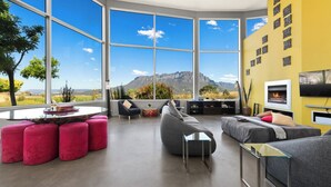 Una sala de estar moderna con ventanas amplias, una chimenea y vistas a la montaña.