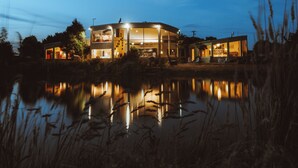 Una casa moderna con un amplio espacio habitable integrado, una escalera a la vista y un reflejo en el agua.