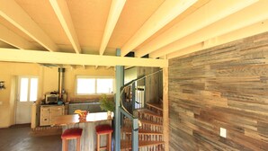 A spacious kitchen with a central island, wooden staircase, and a rustic wall. - Timbarra Hideaway - the perfect retreat (Buchan)