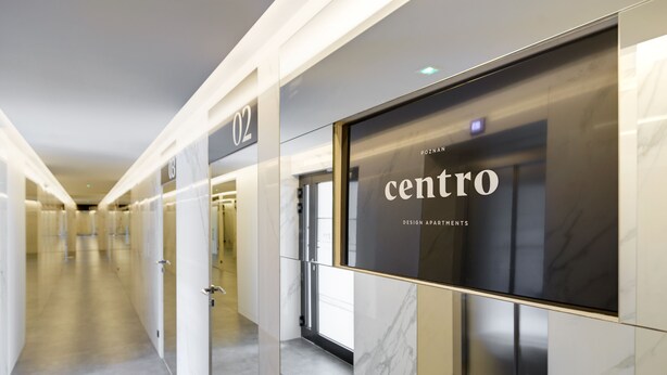 Een moderne gang met een glazen deur met de tekst 'CENTRO DESIGN APARTMENTS'.
