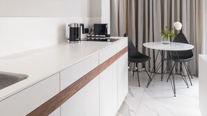 Een moderne keuken met witte kasten, een houten aanrecht en een eethoek met een ronde tafel en stoelen.