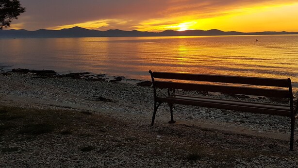 Una panchina accanto a un lago al tramonto.