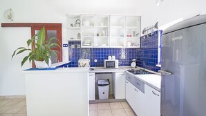Una cucina compatta con frigorifero, microonde, piano cottura e pensili.
