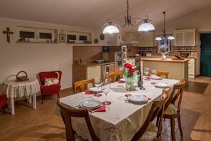 Un coin repas avec une table dressée pour quatre personnes, une chaise rouge et un chat assis sur une chaise rouge.