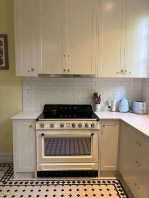 A kitchen with white cabinets, a black stove, and a tiled backsplash.