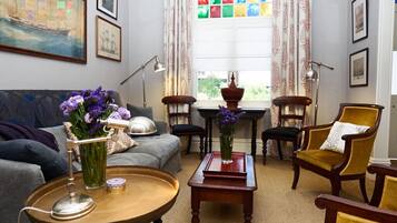 Relax in this inviting living room with a comfortable sofa set, tasteful artwork, and a vibrant stained glass window.