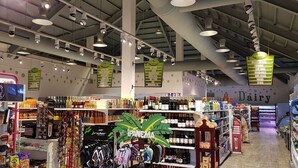 A grocery store interior with various aisles, including a dairy section, and a display of snacks and beverages. - Jamaica Escape 2 Bedroom  Modern Apt. near beaches attractions & restaurants (Ocho Rios)