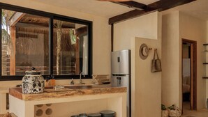 A kitchen with a wooden countertop, a stainless steel refrigerator, and a window with a view of a thatched structure. - Secluded Two-Bedroom Beach House (Tulum)