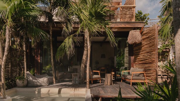 A tropical outdoor area with a pool, wooden furniture, and palm trees. - Secluded Two-Bedroom Beach House (Tulum)