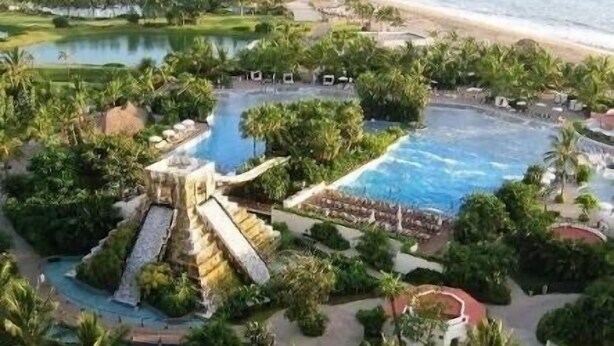 An aerial view of a resort with multiple swimming pools, a waterfall, and a beach. - Súper Condo 3 at Vidanta (Nuevo Vallarta)