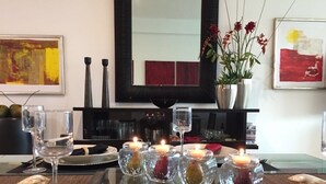 A dining table set with candles, wine glasses, and plates, with a mirror and artwork on the wall. - Súper Condo 3 at Vidanta (Nuevo Vallarta)