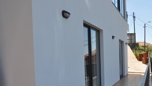 A modern building with a flat facade, large glass doors, and a tiled floor.