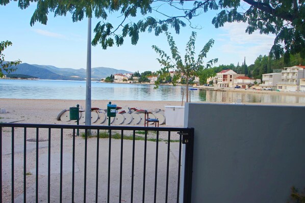 A waterfront property with a view of the sea, a paved area with bicycles, and a gated entrance.