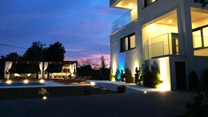 A modern two-story house with a balcony, outdoor seating area, and a well-lit entrance. - Villa Elena - Vinišće (Vinišće)