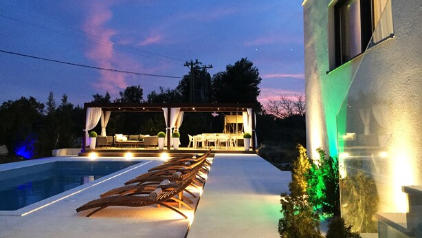 A poolside area with lounge chairs and a covered seating area. - Villa Elena - Vinišće (Vinišće)