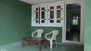 Ein Zimmer mit grünen Wänden, einem Holztisch, zwei weißen Stühlen und einem Fenster mit weißen Läden.