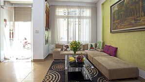 A living room with a sofa, a coffee table with fruit, and a painting on the wall. - Hanoi Friendly House - Superior room - Queensize Bed (Hà Nội)