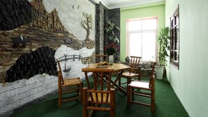 A dining area with a mural, green artificial grass, and wooden furniture. - Hanoi Friendly House - Superior room - Queensize Bed (Hà Nội)