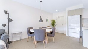 A modern kitchen with white cabinets, a white countertop, and a stainless steel refrigerator. - Le Maison at the Beach (Huskisson)