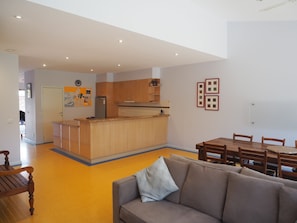 Een moderne keuken met houten kastjes, een inbouw eiland en een eethoek met een houten tafel en stoelen.