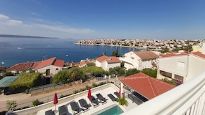 A coastal hotel with a pool, lounge chairs, and a view of the sea and town. - Heated swimming pool, spacious apartment with bay sea view terrace  ap3 (Okrug Gornji)