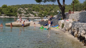 A beach with clear water, people swimming and relaxing, and boats in the background. - Heated swimming pool, spacious apartment with bay sea view terrace  ap3 (Okrug Gornji)
