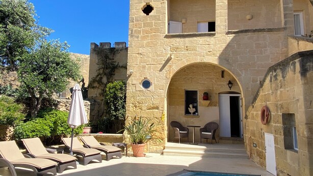 A stone building with a pool, lounge chairs, and a small table with chairs. - Cosy fully renovated farmhouse in Gozo (Xewkija , Gozo)