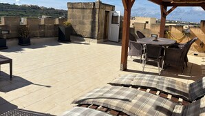 A rooftop terrace with a pergola, outdoor seating, and a view of the cityscape. - Cosy fully renovated farmhouse in Gozo (Xewkija , Gozo)
