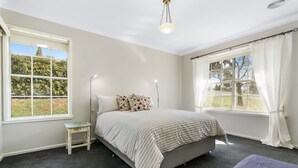 A bedroom with a bed, a nightstand, a window, and a view of the outdoors.